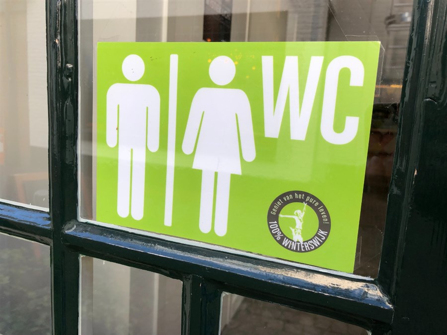 Bordje op raam met symbool man & vrouw en de tekst 'wc'